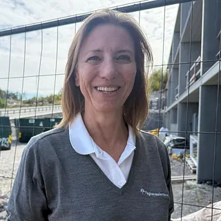 Kvinne med halvlangt blondt hår og grå genser
